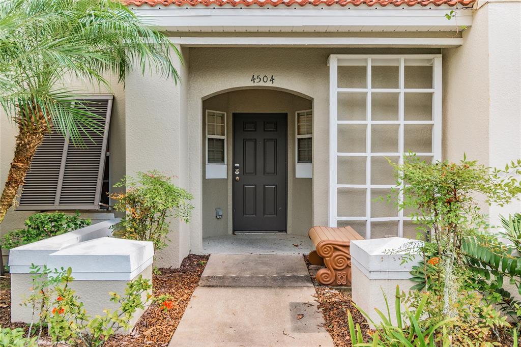 The front entrance features a dark door, a concrete walkway, and a decorative white lattice — 4504 ALBERTO CIRCLE, KISSIMMEE, FL