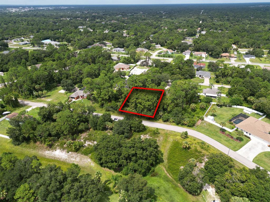 An aerial view shows a rectangular, tree-covered vacant lot outlined in red within a neighborhood — FEARS STREET, NORTH PORT, FL