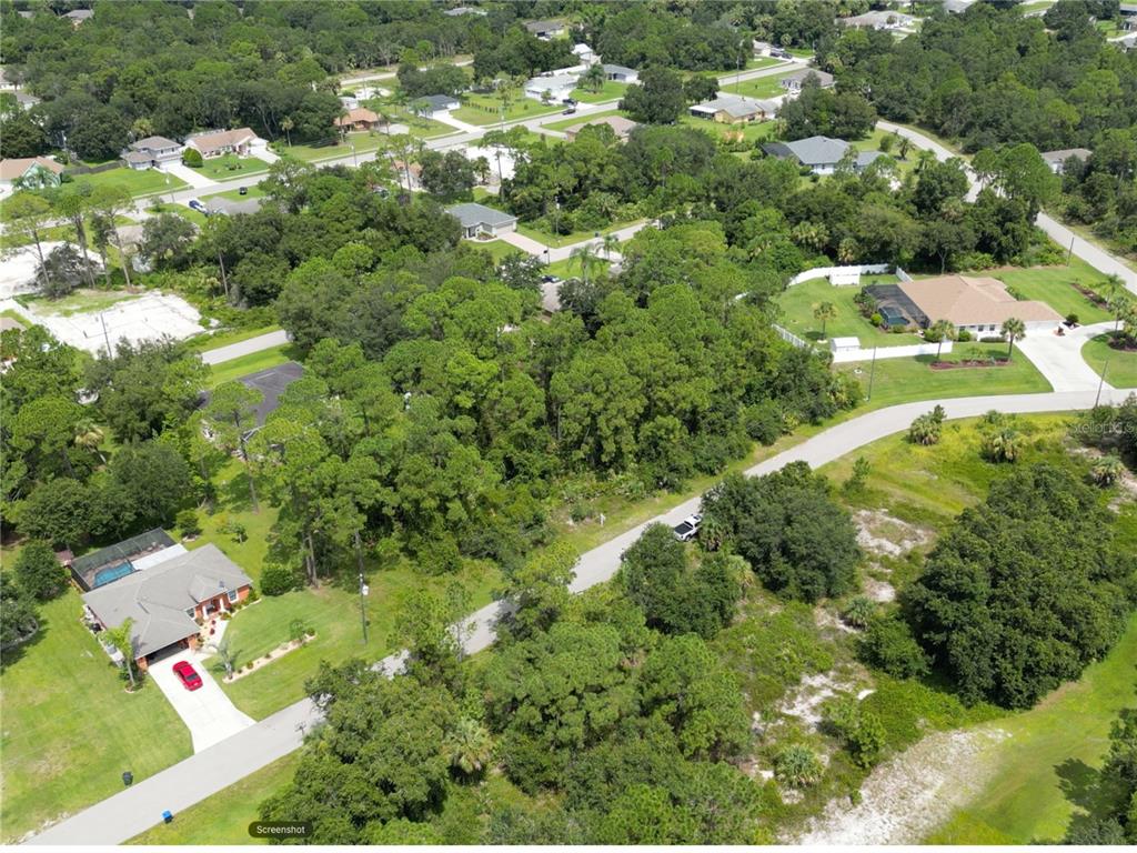 An aerial view shows a residential street surrounded by dense trees and several single-family homes — FEARS STREET, NORTH PORT, FL
