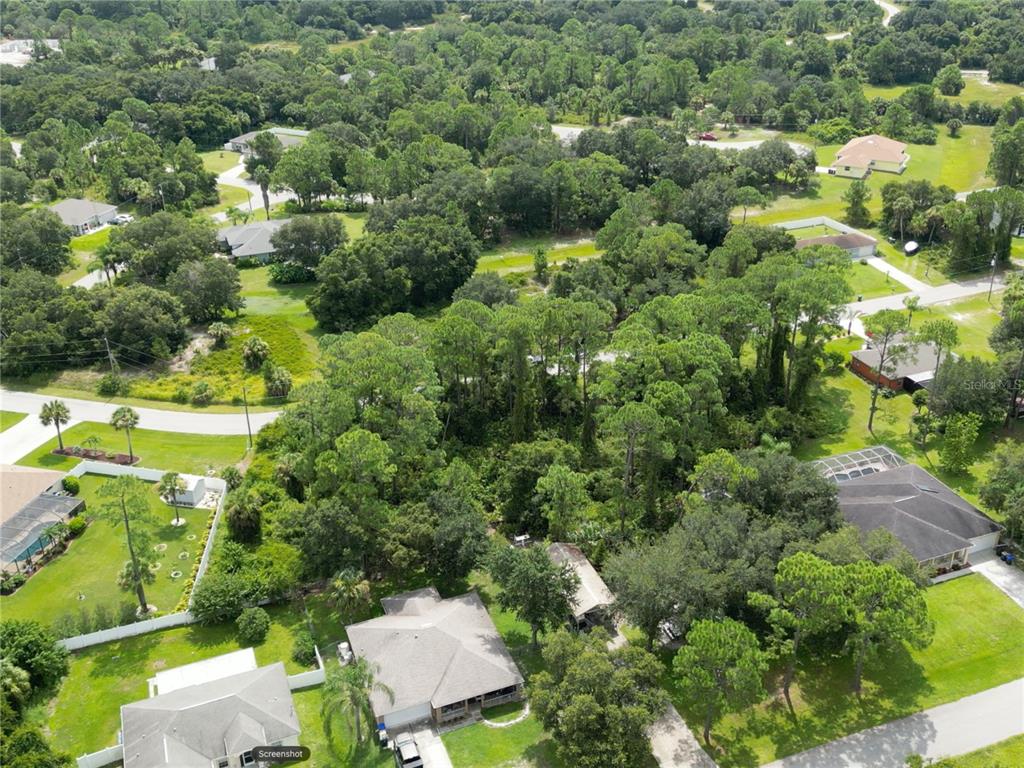 An aerial view shows a wooded residential lot surrounded by houses and paved streets — FEARS STREET, NORTH PORT, FL