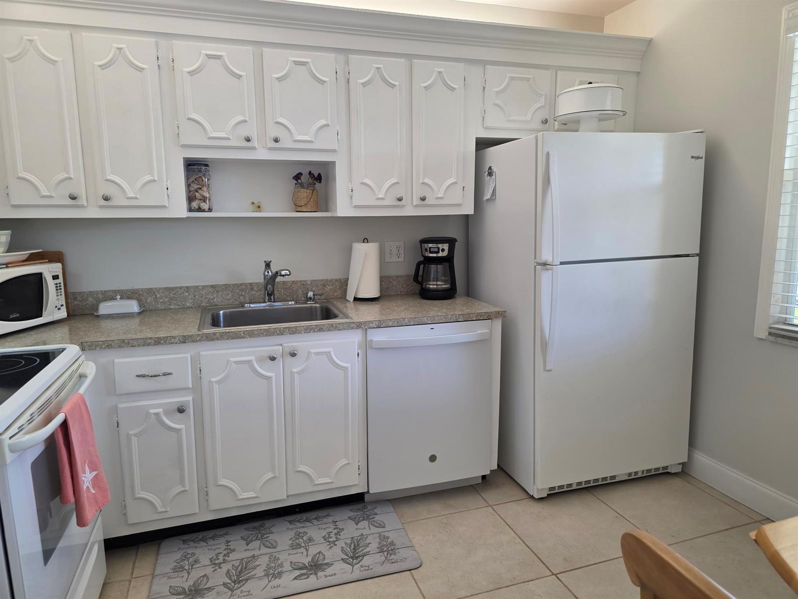 A kitchen with white cabinets, a stainless steel sink, a dishwasher, and a white refrigerator — 717 S Us Highway 1 # 211, Jupiter FL 33477, JUPITER, FL