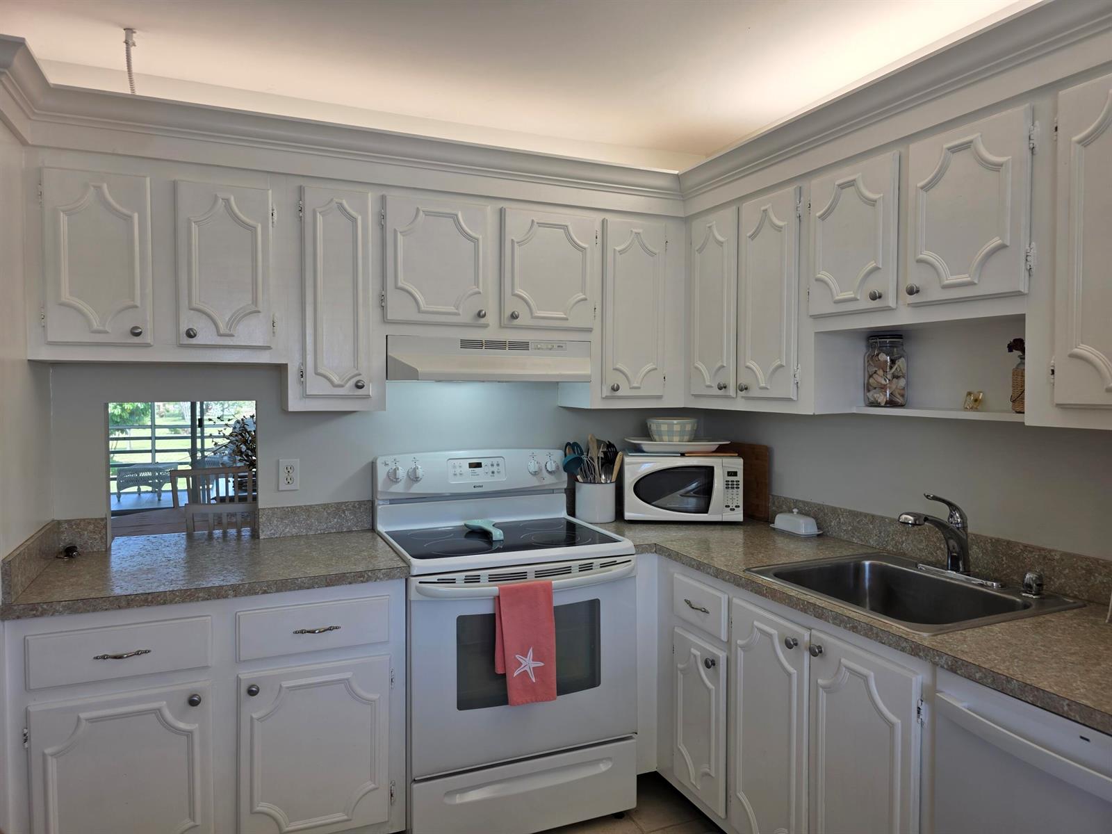 A kitchen features white cabinetry, a white stove, a stainless steel sink, and laminate countertops — 717 S Us Highway 1 # 211, Jupiter FL 33477, JUPITER, FL