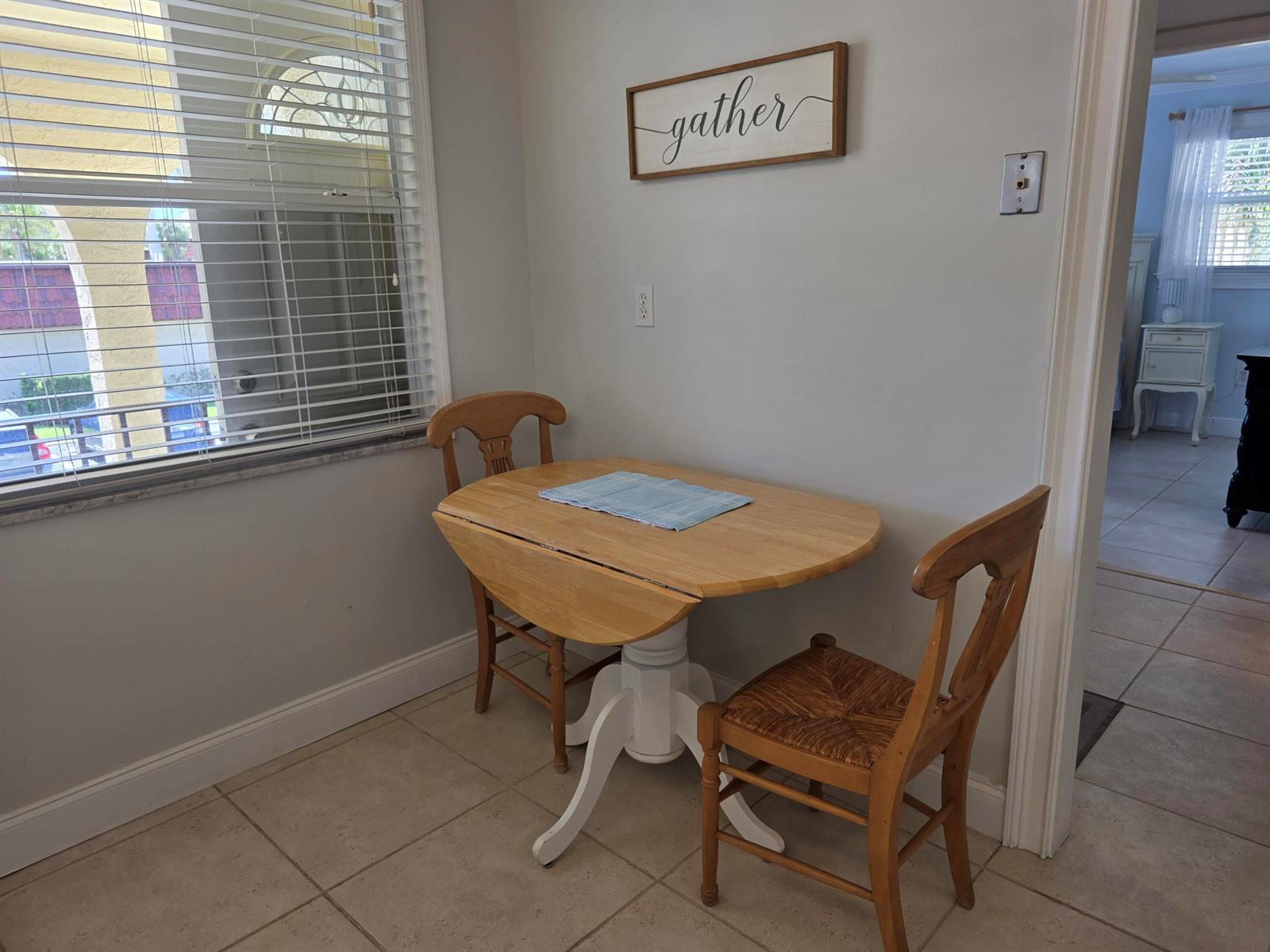 A small dining nook features a drop-leaf table, two wooden chairs, and a wall sign — 717 S Us Highway 1 # 211, Jupiter FL 33477, JUPITER, FL