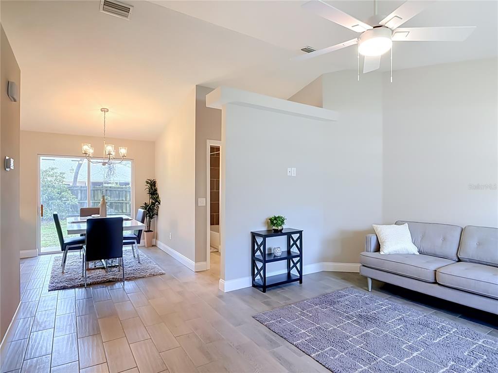 A living room and dining area feature light wood-look tile flooring and a ceiling fan — 1472 4TH STREET, ORANGE CITY, FL