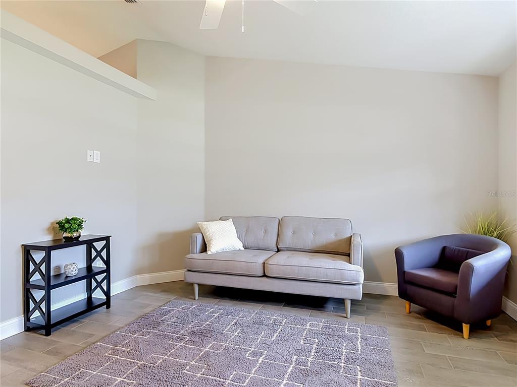 A living room features a gray sofa, a dark armchair, a rug, and a black shelf — 1472 4TH STREET, ORANGE CITY, FL