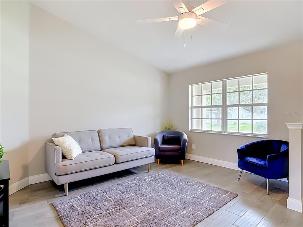 A living room features a gray sofa, two accent chairs, a rug, and a ceiling fan — 1472 4TH STREET, ORANGE CITY, FL