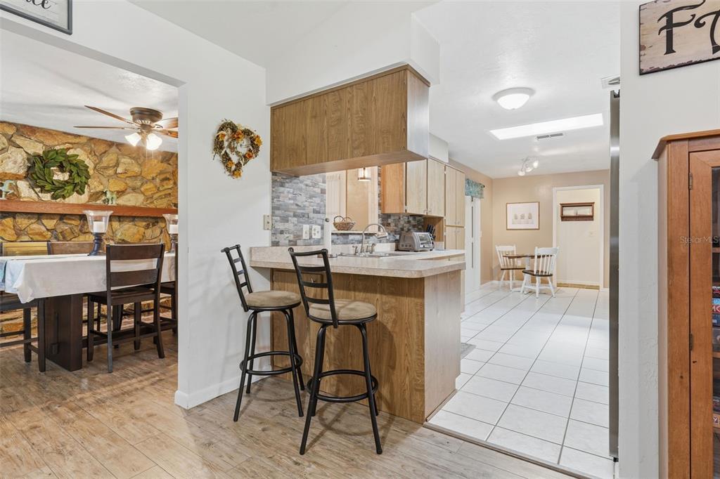 A kitchen with a breakfast bar, wood cabinets, and tile flooring, adjacent to a dining area — 42 S J KELLNER BOULEVARD, BEVERLY HILLS, FL