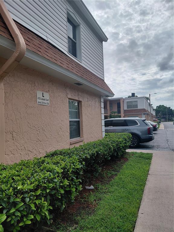 A two-story building with pink stucco, white siding, and a hedge in the foreground — 4725 JOSEPH COURT UNIT 229, TAMPA, FL