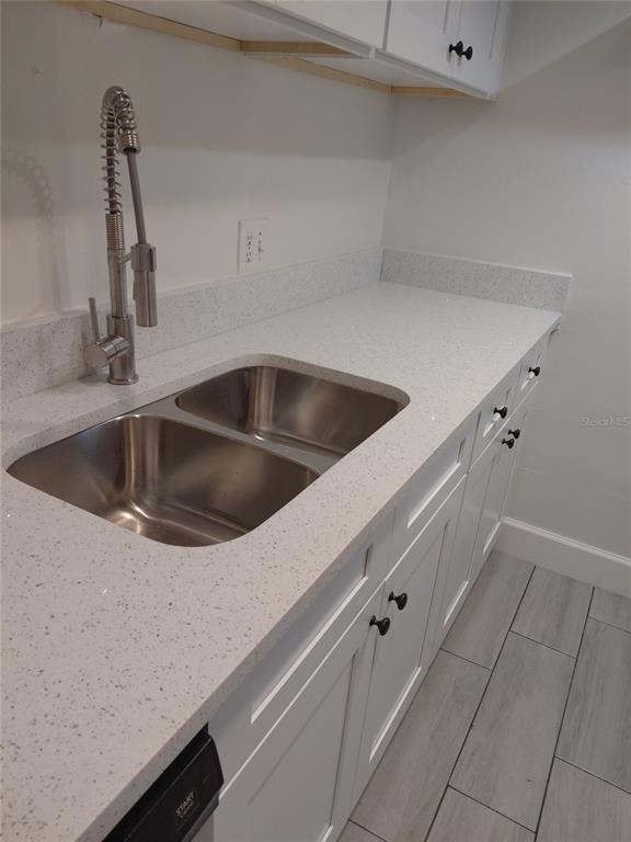 A kitchen features white cabinets, a speckled quartz countertop, a stainless steel sink, and faucet — 4725 JOSEPH COURT UNIT 229, TAMPA, FL
