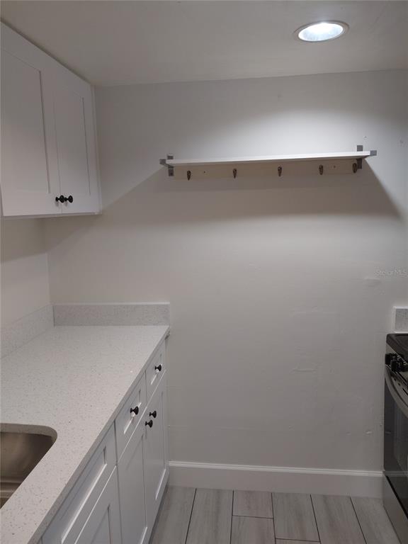 A kitchen features white cabinets, a speckled countertop, a sink, and a wall-mounted coat rack — 4725 JOSEPH COURT UNIT 229, TAMPA, FL