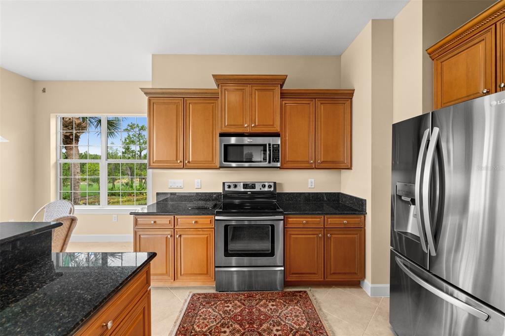 A screened-in balcony with tile flooring, ceiling fans, and a view of a pond — 10391 GLASTONBURY CIRCLE UNIT 202, FORT MYERS, FL