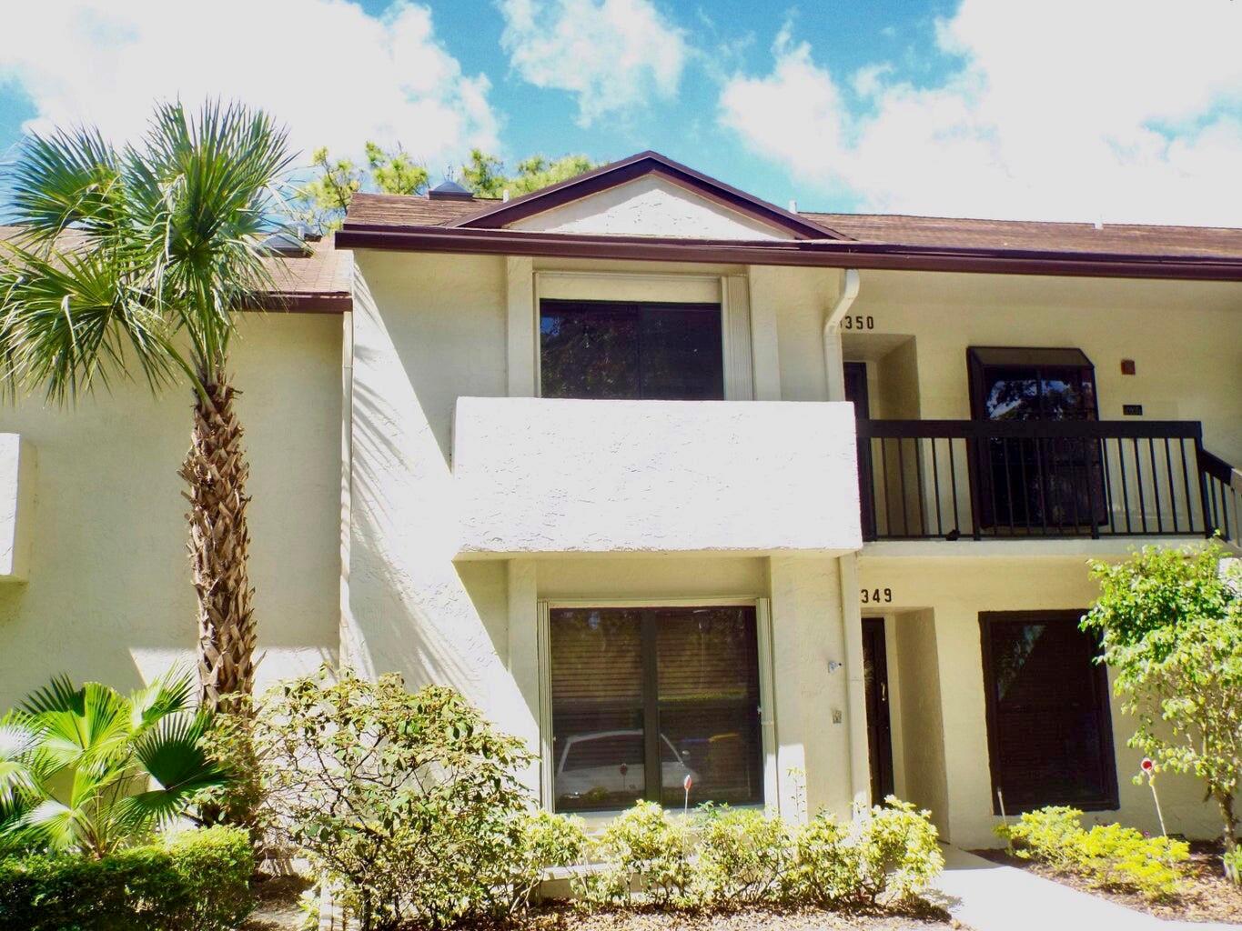 A two-story stucco apartment building features a palm tree, balconies, and dark-framed windows — 3350 Perimeter Drive # 1323, FL 33467, FL