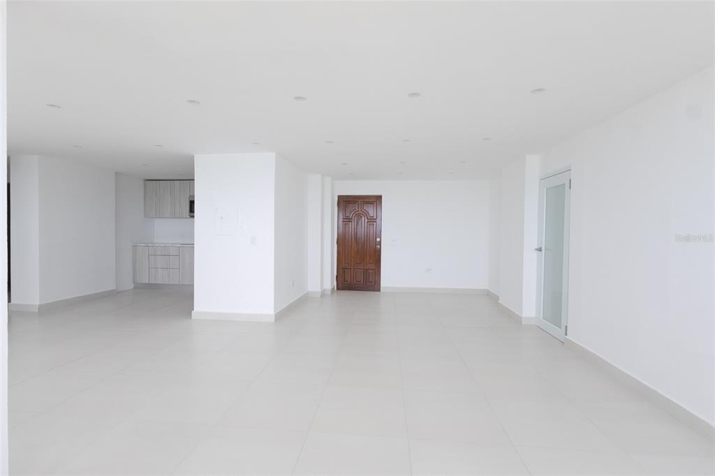 An open-plan living area features white walls, light-colored tile flooring, and a small kitchen corner — PH 807B PLAYA DORADA, CAROLINA, PR