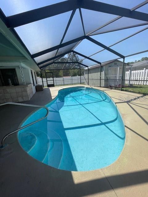 A screened-in backyard features a kidney-shaped swimming pool and a small storage shed — 17 PECAN PASS TERRACE, OCALA, FL