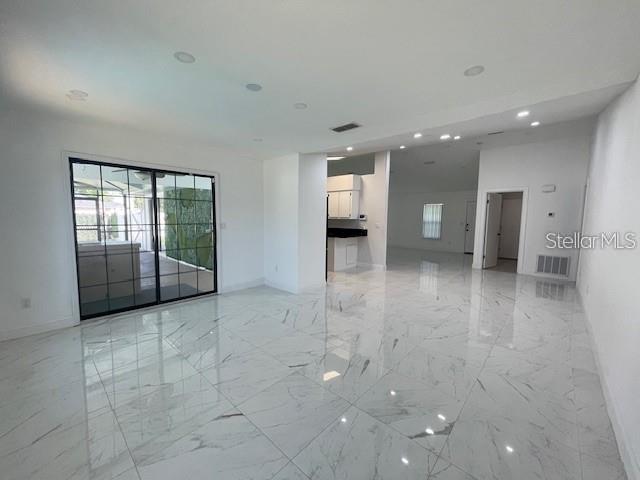 A spacious room features white marble-look tile flooring, recessed lighting, and a large sliding glass door — 17 PECAN PASS TERRACE, OCALA, FL