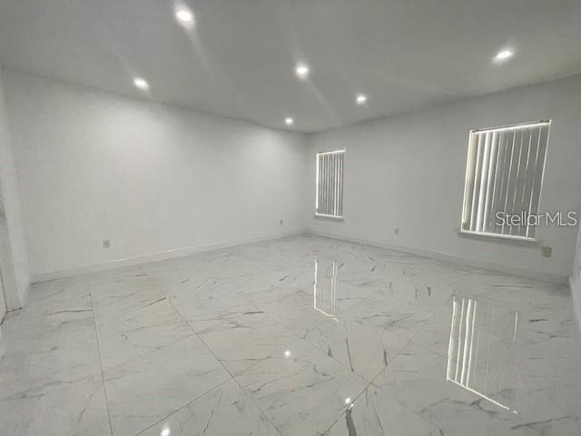 An empty room features white walls, recessed lighting, and polished white marble-look tile flooring — 17 PECAN PASS TERRACE, OCALA, FL