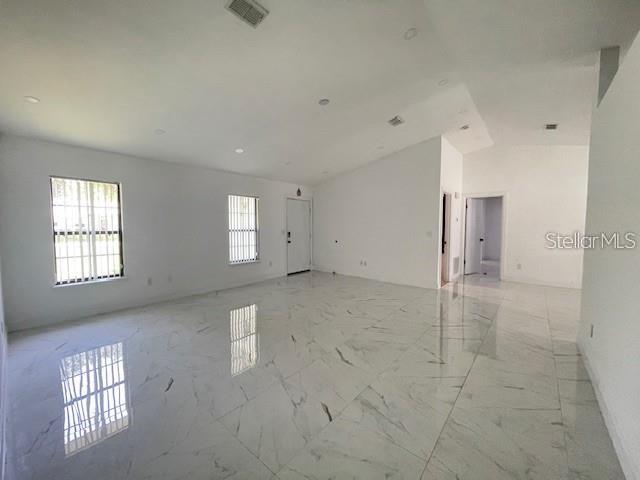An empty room with white walls, recessed lighting, and polished white marble-look tile flooring — 17 PECAN PASS TERRACE, OCALA, FL