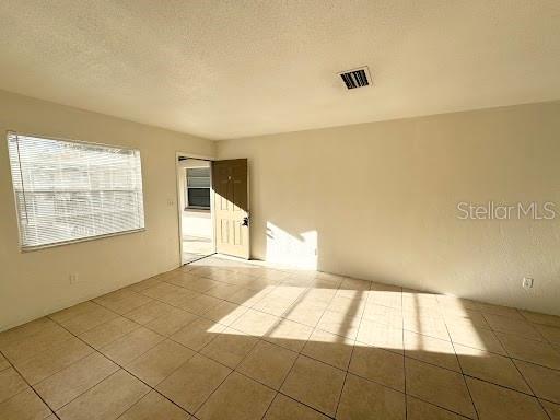 A room with light-colored tile flooring, beige walls, a window with blinds, and an open doorway — 1221 KENNEDY ROAD UNIT 48, DAYTONA BEACH, FL