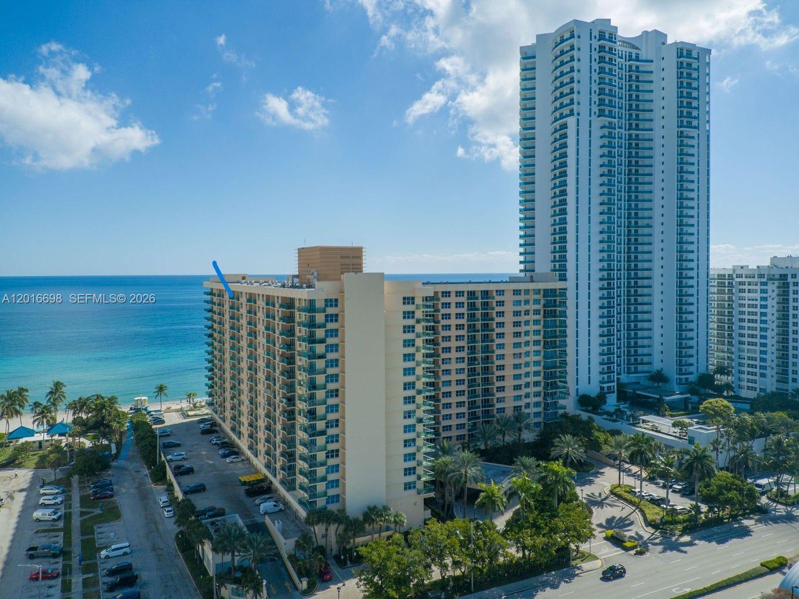 An aerial view shows a tall beachfront residential building with a blue arrow pointing upward — 2501 S Ocean Dr, Hollywood FL 33019, HOLLYWOOD, FL