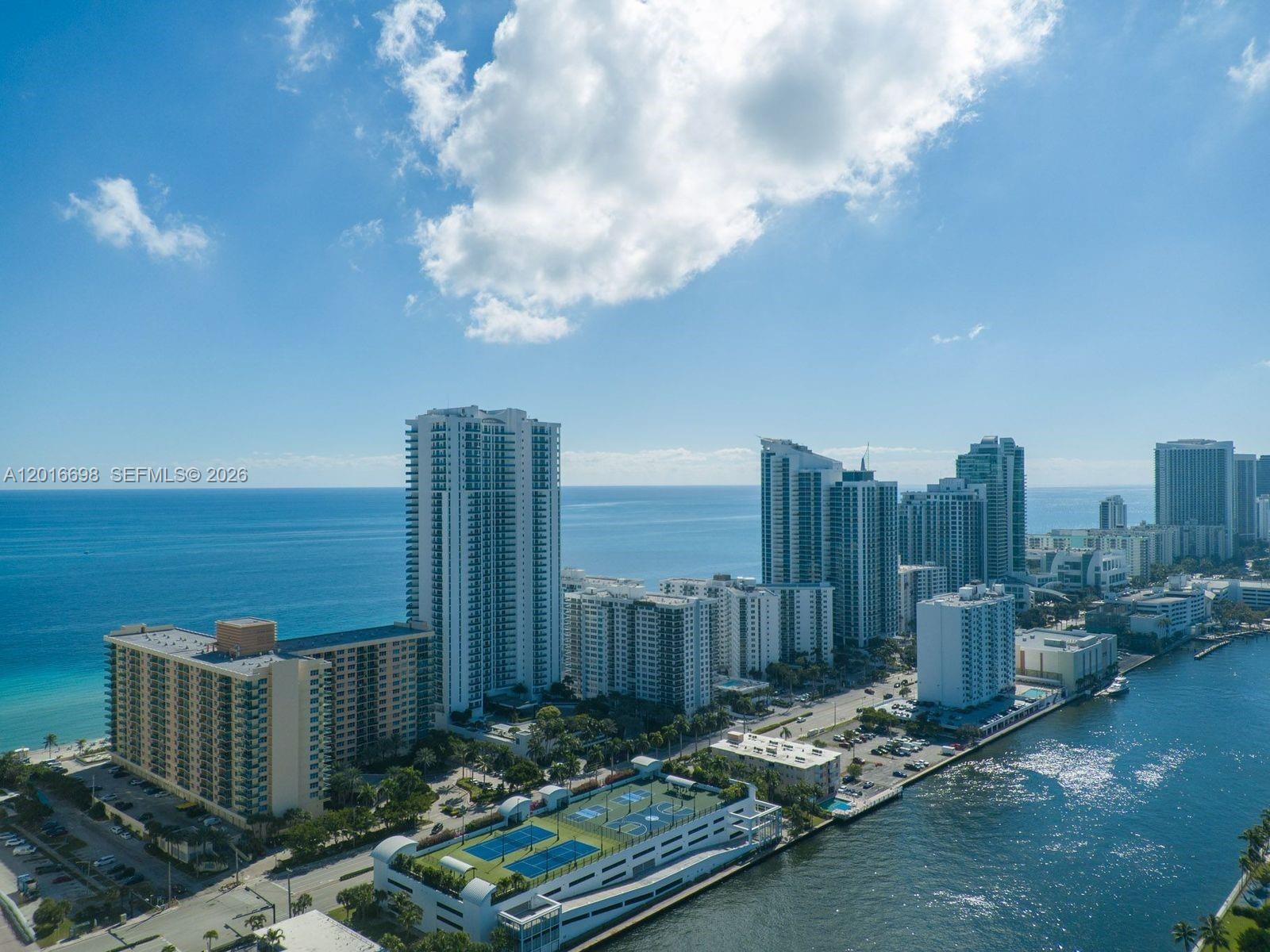 An aerial view shows high-rise residential buildings along a coastline with a tennis court below — 2501 S Ocean Dr, Hollywood FL 33019, HOLLYWOOD, FL