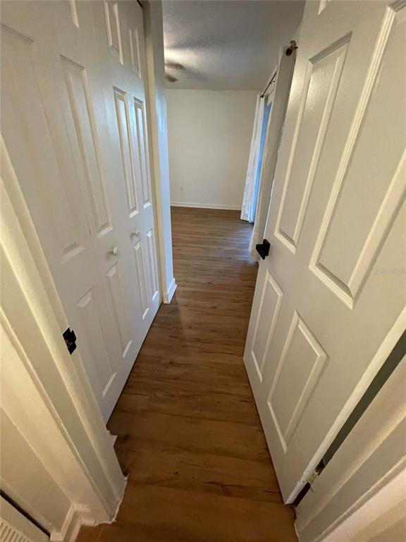 A hallway with wood-look flooring leads to a bedroom featuring white paneled doors — 23108 DOVER DRIVE, LAND O LAKES, FL