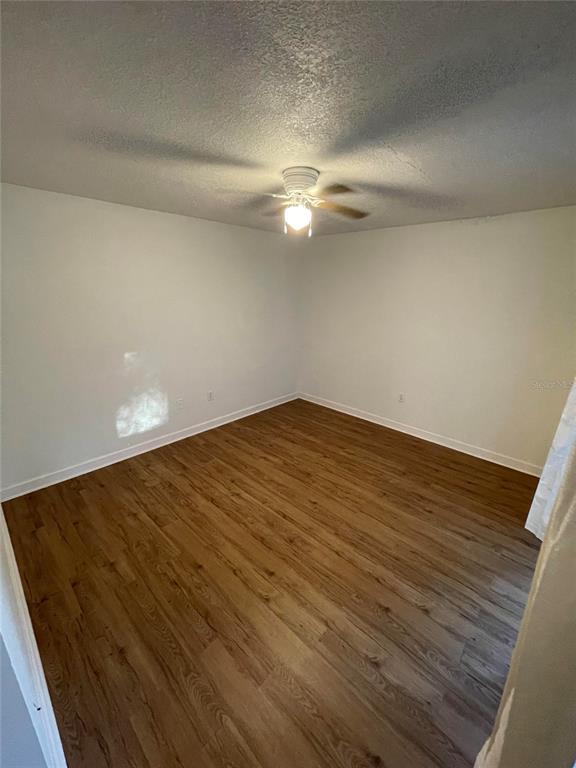 An empty bedroom features light-colored walls, a ceiling fan, and wood-look laminate flooring — 23108 DOVER DRIVE, LAND O LAKES, FL