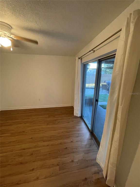 A room with wood-look flooring, a ceiling fan, and sliding glass doors leading outside — 23108 DOVER DRIVE, LAND O LAKES, FL
