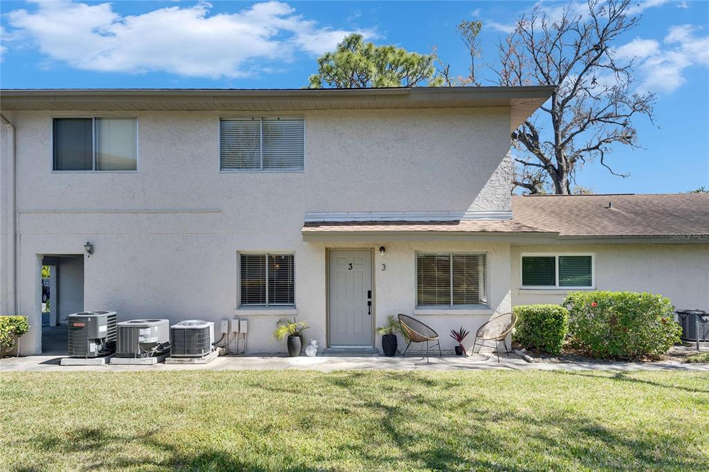 The exterior of a two-story residential building features a gray front door and three air-conditioning units — 1828 BOUGH AVENUE UNIT 3, CLEARWATER, FL