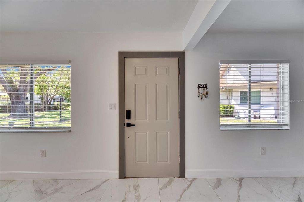 A front entryway features a light-colored door, white walls, and white marble-patterned tile flooring — 1828 BOUGH AVENUE UNIT 3, CLEARWATER, FL