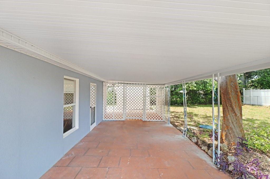 A covered patio with a tiled floor, white lattice privacy screen, and metal support columns — 39038 HEATH DRIVE, ZEPHYRHILLS, FL