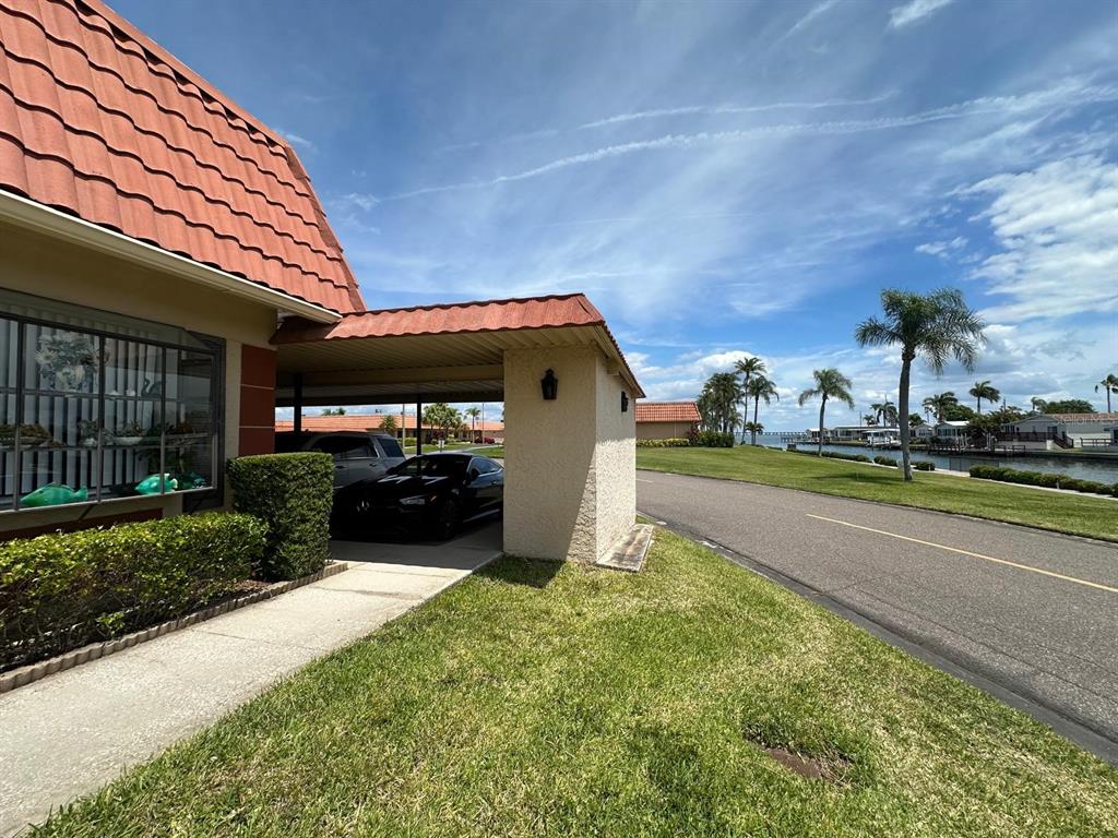 A view of a house exterior with a carport, a black car, and a waterfront canal — 19029 US HIGHWAY 19 N UNIT 21F, CLEARWATER, FL