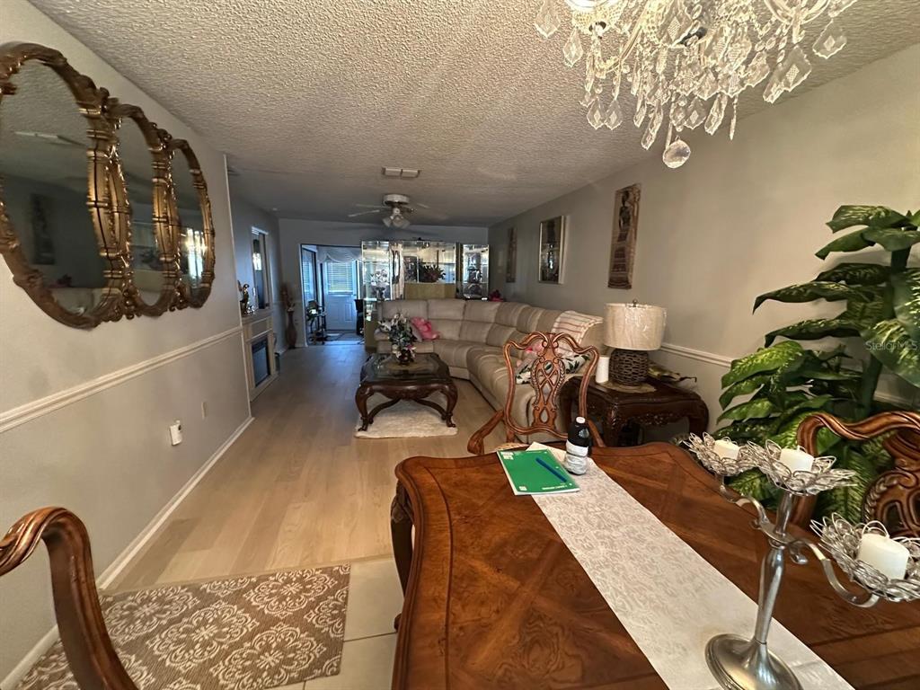 A dining area with a wood table leads into a living room with a sectional sofa — 19029 US HIGHWAY 19 N UNIT 21F, CLEARWATER, FL