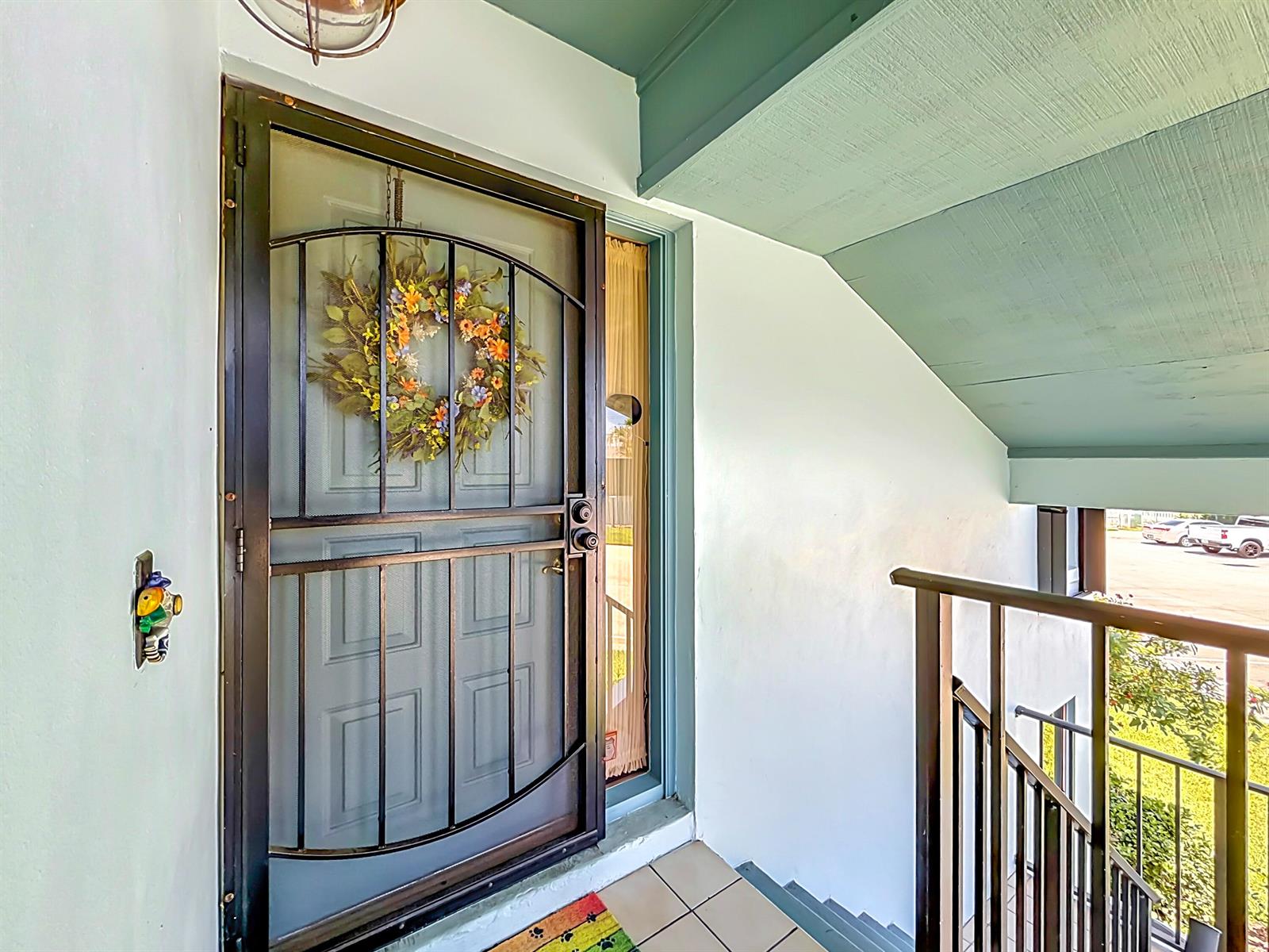 A front door with a decorative metal security screen and wreath opens onto a landing — 950 S Kanner Highway # 308, Stuart FL 34994, STUART, FL