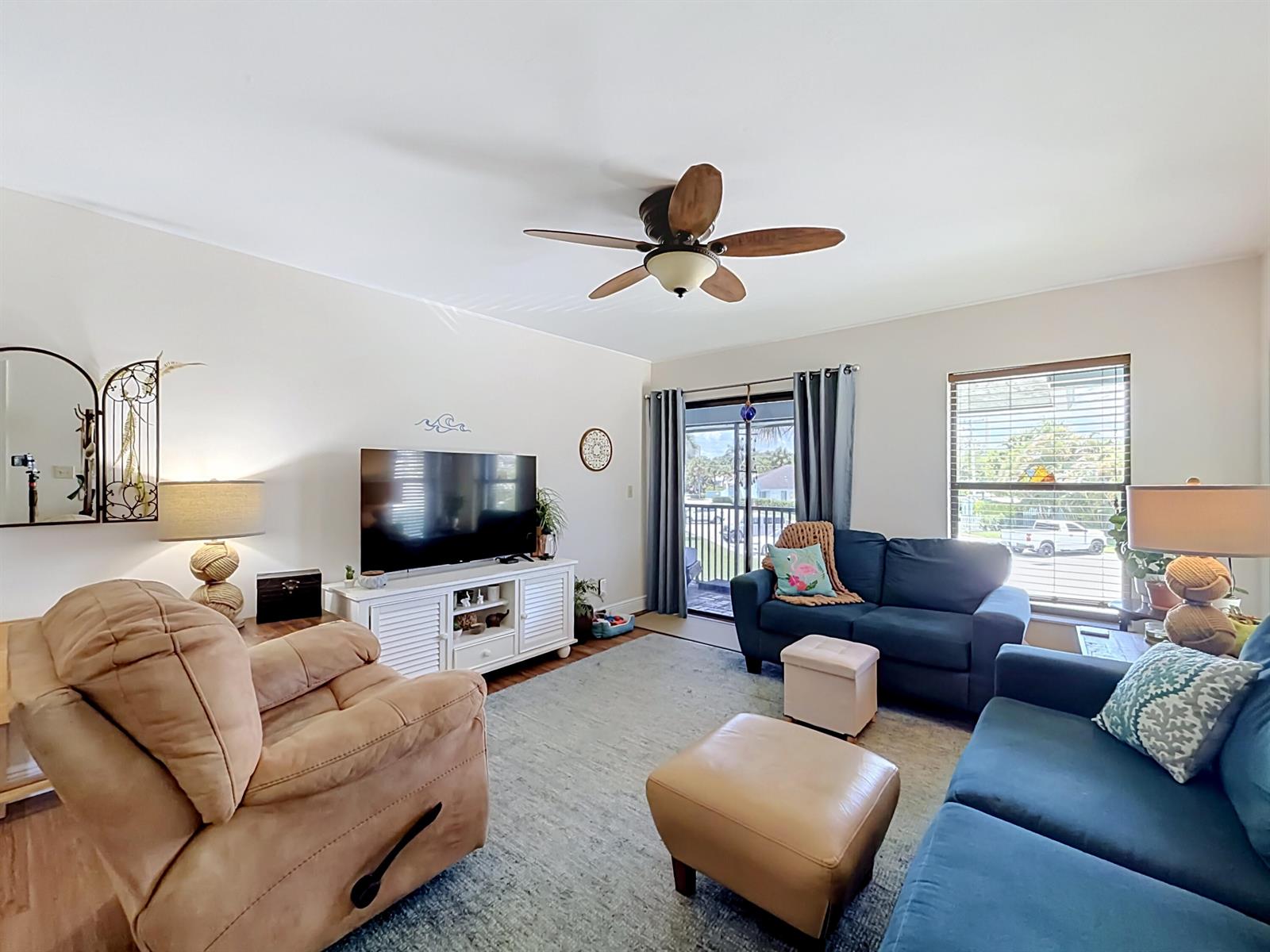 A living room features a tan recliner, blue sofa, television, and a ceiling fan — 950 S Kanner Highway # 308, Stuart FL 34994, STUART, FL