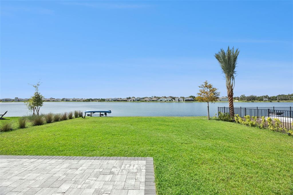 A backyard with a paved patio, green lawn, and a view of a lake — 13557 MCMILLAN DRIVE, ORLANDO, FL