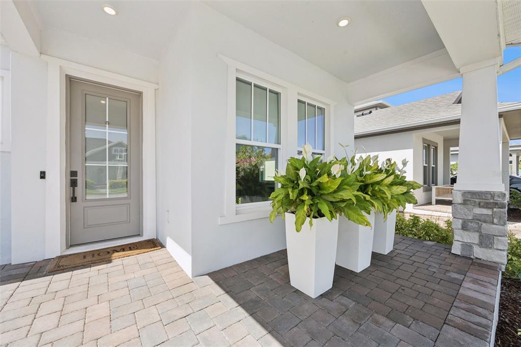 A covered front porch features a gray door, white walls, and three white potted plants — 13557 MCMILLAN DRIVE, ORLANDO, FL