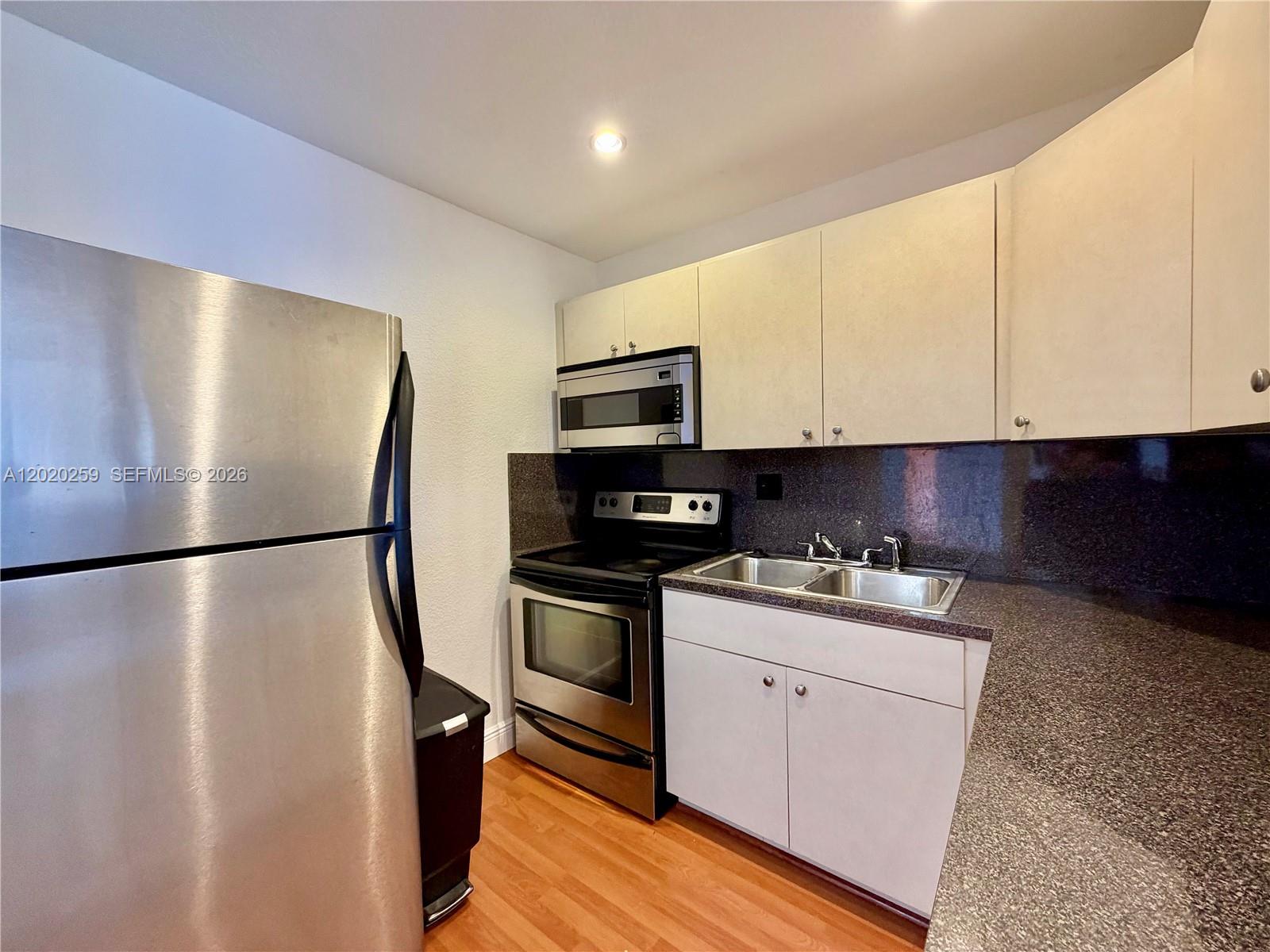 A small kitchen features stainless steel appliances, white cabinets, and dark granite countertops — 9429 SW 76th St # W38, Miami FL 33173, MIAMI, FL