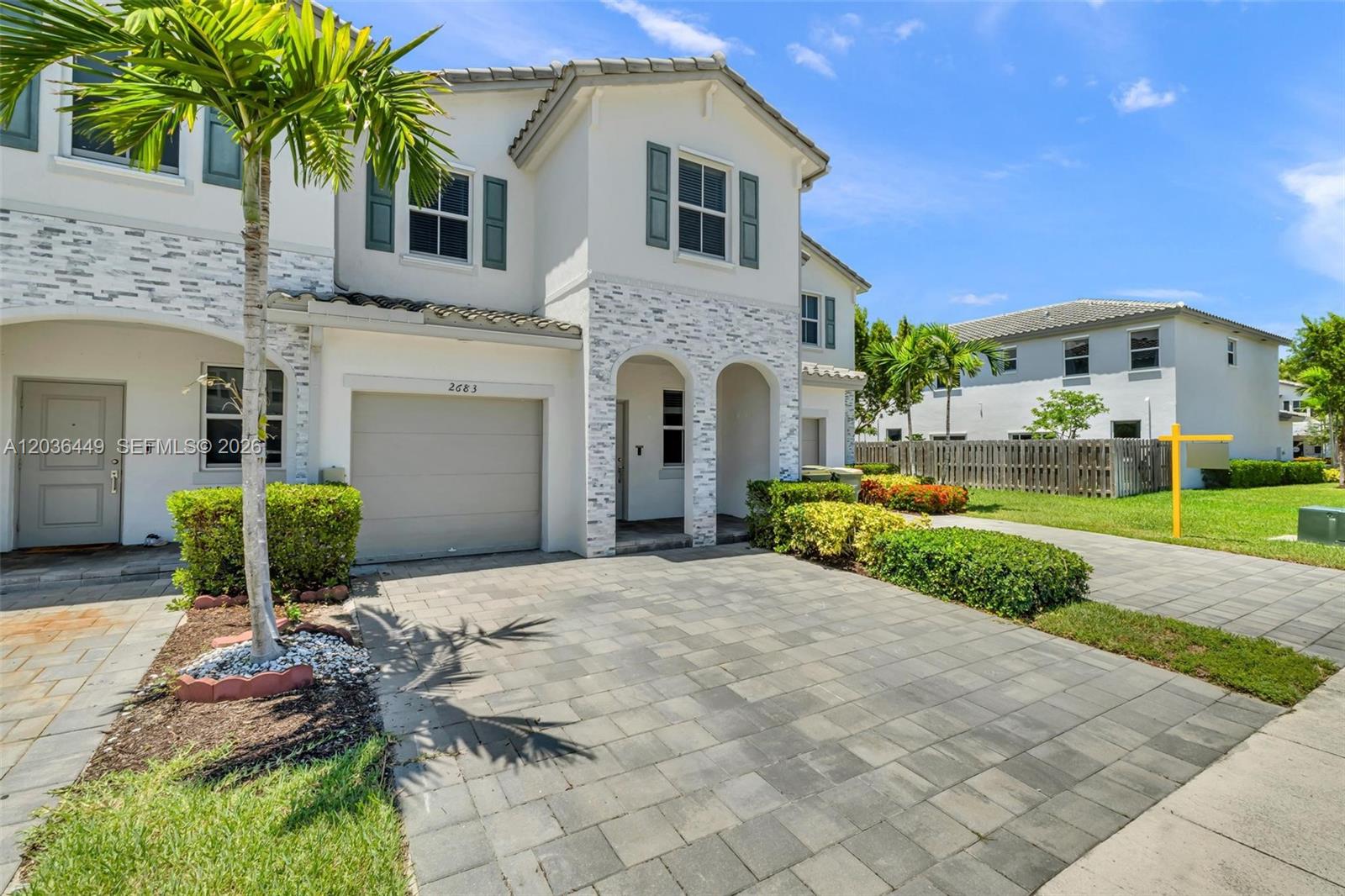 A two-story townhouse features a paved driveway, a garage, and light-colored stone facade accents — 2683 SE 12th St, Homestead FL 33035, HOMESTEAD, FL