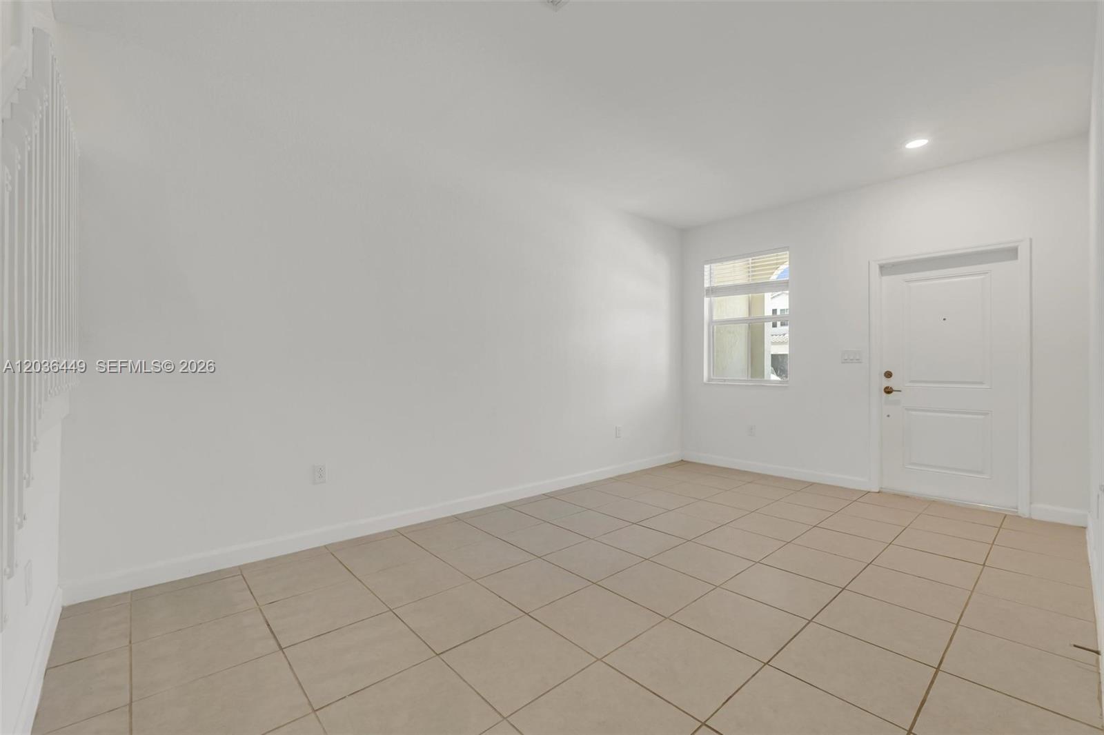 An empty room features white walls, a single window, a white door, and tiled flooring — 2683 SE 12th St, Homestead FL 33035, HOMESTEAD, FL