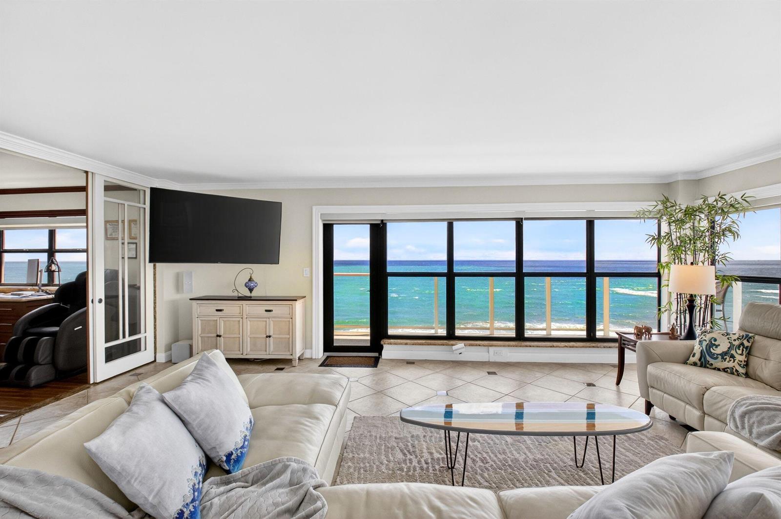 A living room features light tile floors, a surfboard coffee table, and large ocean-view windows — 4605 S Ocean Boulevard # 5a, Highland Beach FL 33487, HIGHLAND BEACH, FL