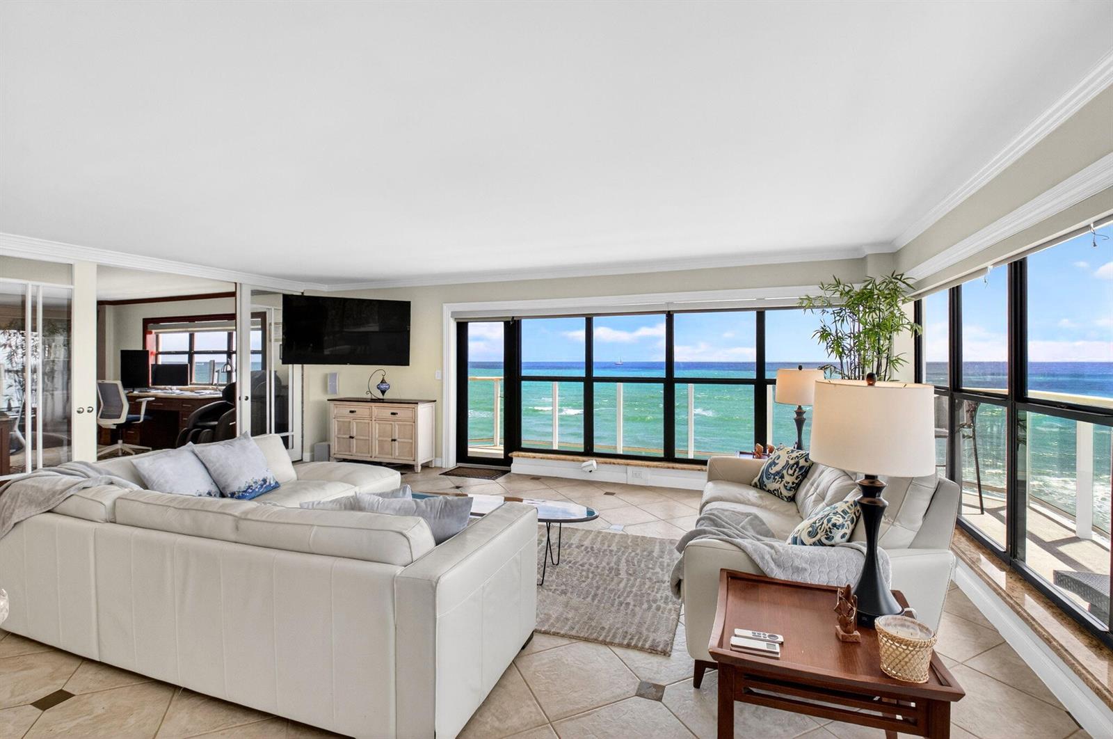 A living room with white leather sofas, tile floors, and large windows overlooking the ocean — 4605 S Ocean Boulevard # 5a, Highland Beach FL 33487, HIGHLAND BEACH, FL