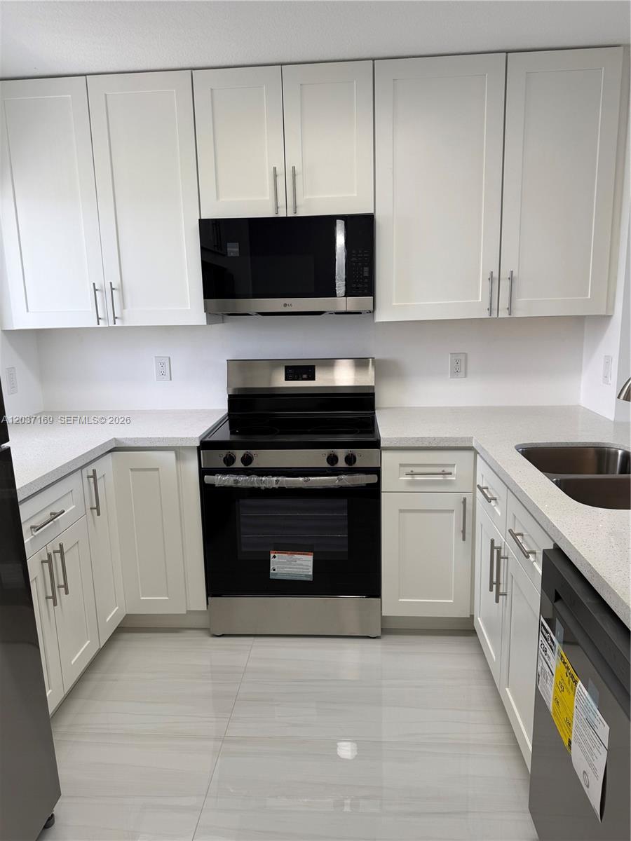 A modern kitchen features white shaker cabinets, stainless steel appliances, and light-colored countertops — 8710 N Sherman Cir # 506, Miramar FL 33025, MIRAMAR, FL