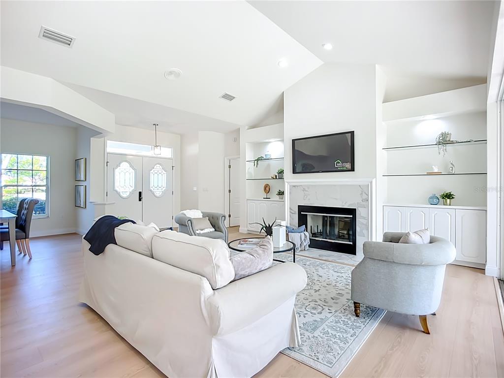A living room features a white sofa, two armchairs, a fireplace, and built-in shelving — 2960 SANDRINGHAM PLACE, SARASOTA, FL