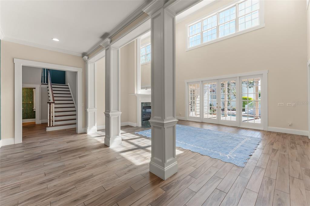 A spacious living room features tall white columns, light wood floors, and a large blue rug — 403 WATER STREET, CELEBRATION, FL