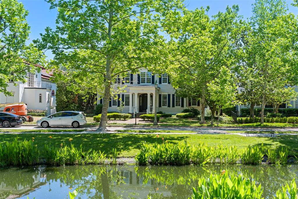 A two-story house with black shutters sits behind a pond and large trees — 403 WATER STREET, CELEBRATION, FL
