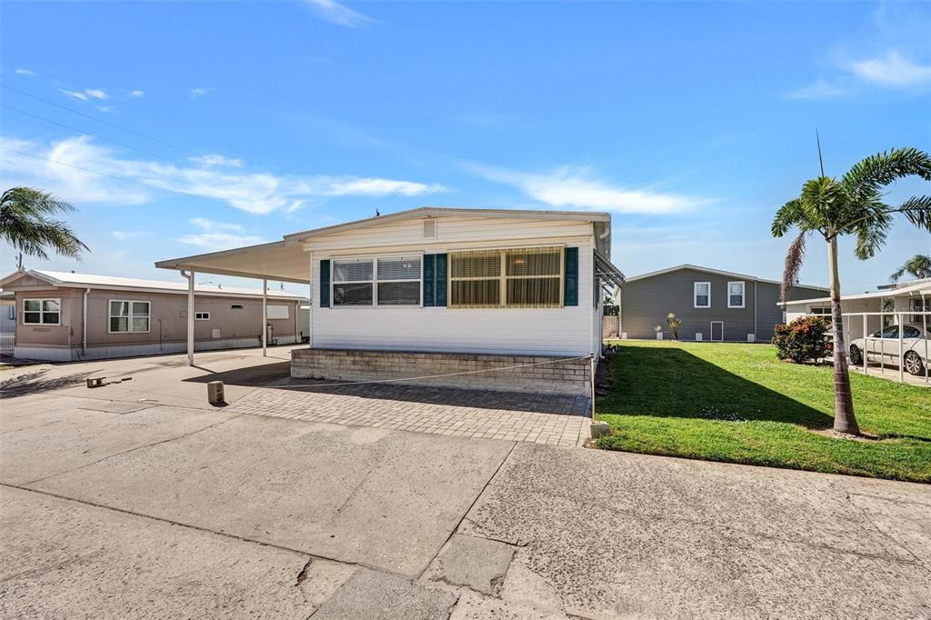 A white mobile home features a carport, a brick foundation, and a paved driveway — 10315 CORTEZ ROAD W UNIT 19H, BRADENTON, FL