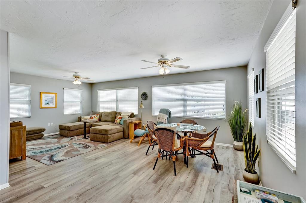 A living and dining area with light wood flooring, a sectional sofa, and ceiling fans — 10315 CORTEZ ROAD W UNIT 19H, BRADENTON, FL