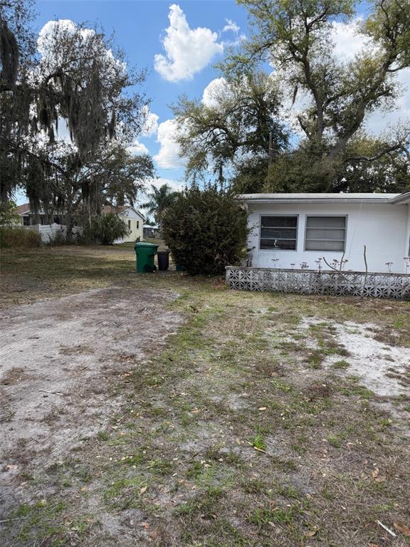 A side view of a white house with a decorative concrete block wall and yard — 5819 HOWARD LANE, PUNTA GORDA, FL