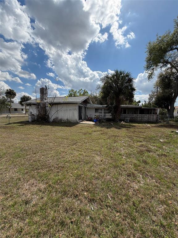A single-story house with a brick chimney and a covered patio sits on a grassy lot — 5819 HOWARD LANE, PUNTA GORDA, FL