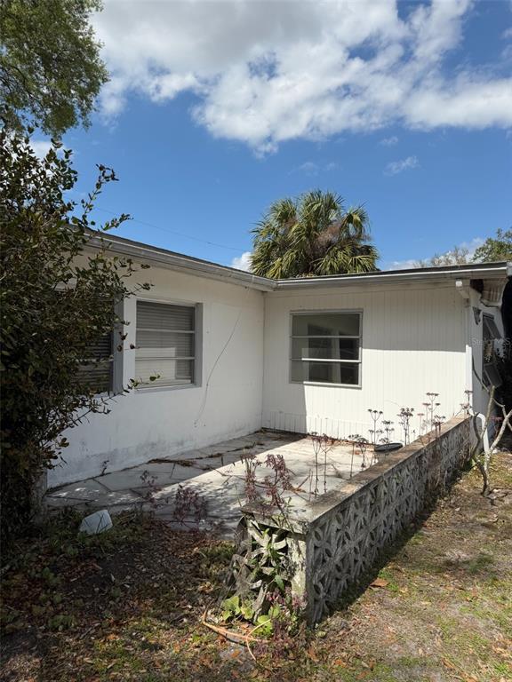 The exterior of a white house features a concrete patio enclosed by a decorative block wall — 5819 HOWARD LANE, PUNTA GORDA, FL